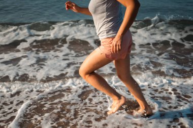 Sahildeki eğitimi sırasında ayakları suyun içinde koşan bir koşucu..