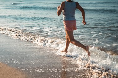 Kararlı bir kadın sahilde egzersiz yapıyor, su kenarında aktif ve sağlıklı bir yaşam tarzını benimsiyor..