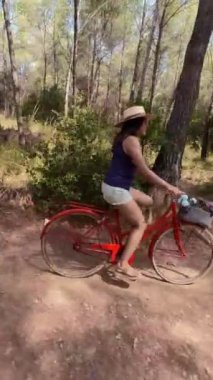 Ormanda klasik kırmızı bir bisikletle gezen bir kadının yan görüntüsü..