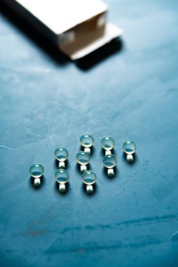 Yumuşak kapsüller mavi bir arkaplan üzerinde düzenlenmiş yan ambalajları ile.