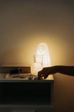 Bir insanın eli geceleri masadan ilaç alır..