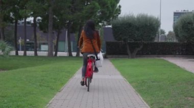 Klasik kırmızı bisikletli bir kadın işe giderken karşıdan karşıya geçiyor..