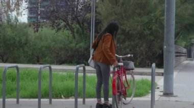 Resmi giyinmiş bir kadın işe gitmek için kırmızı bisikletini park eder..