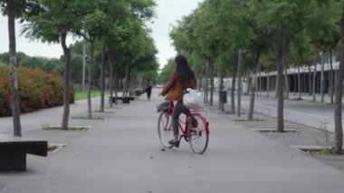 Kadın gideceği yere varır, bisikletini park eder ve işe koşar..