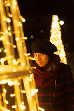 Geceleri şehrinde Noel süsleriyle çevrili bir kadın..