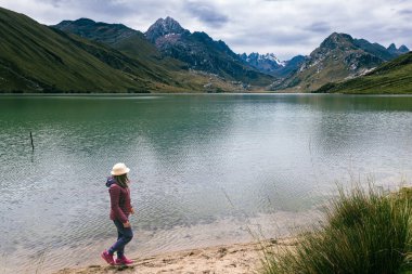 A woman looks out over the landscape at Querococha Lagoon in Peru. clipart