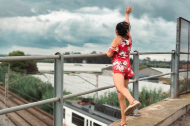 Köprüden gelen trene el sallayan kadın.