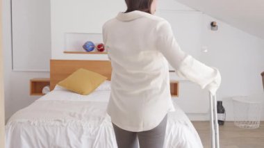 Bir kadın tatil evine geliyor, rahatlığı yaşıyor ve yatakta dinleniyor..