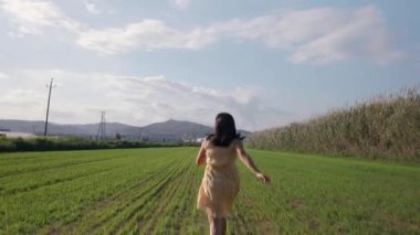 Kadın koşar ve yeşil bir tarladan atlar..