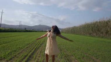 Bir kadın yeşil bir alanda dönüyor, rahatlama işareti olarak..