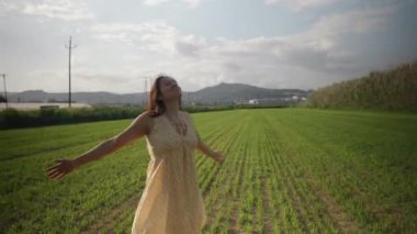 Çimlerle dolu yeşil bir alanda eğlenen bir kadın..