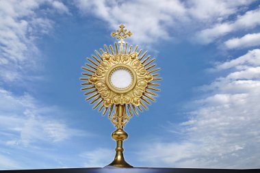 Monstrance for adoration in a Catholic church ceremony - Adoration of the Blessed Sacrament - religious symbol on background with blue sky heart shaped