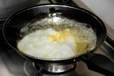 Kızarmış yumurta ve fırının tavasında bol miktarda yağ ve tereyağı var.