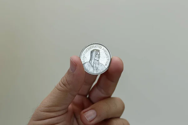 swiss five franc coin between fingers - swiss franc coin