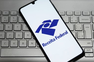 Minas Gerais, Brezilya - 28 Eylül 2023: Brezilya Federal Gelirli akıllı telefon ekranı ve birkaç Brezilyalı reel banknot