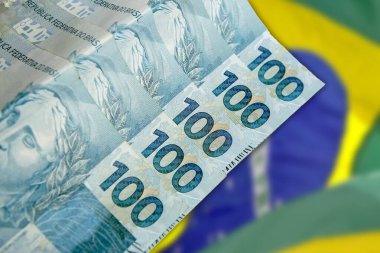 Ulusal bayrağın önündeki 100 Real Brazilya banknotunu kapat. Finans ve iş konsepti