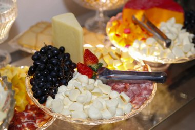 Tepside çeşitli soğuk yiyecekler, peynirler, abur cuburlar ve salam var.