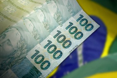 Ulusal bayrağın önündeki 100 Real Brazilya banknotunu kapat. Finans ve iş konsepti