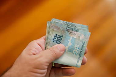 Brezilya 'da finans, ekonomi, yatırım ve zenginlik temaları için mükemmel olan 100 Brezilyalı gerçek banknotu tutan elin keskin görüntüsü