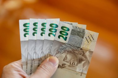 Brezilya 'da para, finans, ekonomi ve alım gücünü sembolize eden 200 reais banknot tutan el resmi