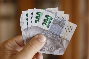 El ele tutuşmanın görüntüsü 200 reais banknot, para, finans, satın alma gücü ve Brezilya ekonomisini sembolize ediyor.