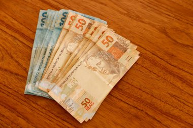 Brezilya 'da finans, ekonomi ve zenginlik temaları için ideal, kırsal ahşap masaya yayılmış yüz elli gerçek banknot açın