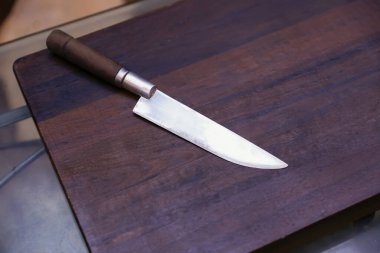 Kırsal ahşap tezgahta parlak bıçaklı bıçak, kusursuz kesim ve sıcak mutfak düzeni için mükemmel.