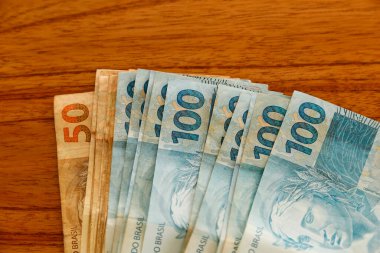 Brezilya 'da para, kişisel finans, bütçe ve zenginlik kavramları için mükemmel, kırsal ahşap yüzeye yayılmış yüz Brezilya gerçek banknotları