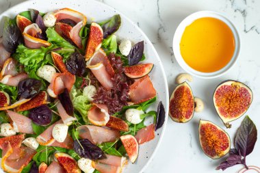 İtalyan restoranında taze doğranmış salata, mozzarella, incir, prosciutto veya jamon. Üst görünüm, menü konsepti ya da aşındırıcı. Beyaz mermer arkaplan
