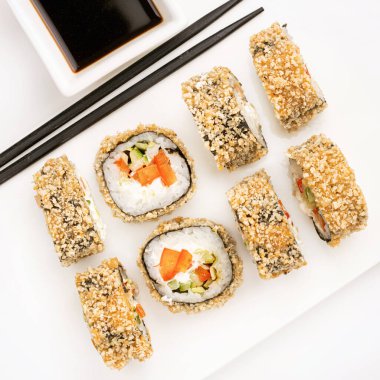 Yukarıdan gelen beyaz arka planda sebzeli suşi ruloları. Geleneksel Japon mutfağının en iyi manzarası. Yemek çubuğu dizaynlı Asya yemekleri.