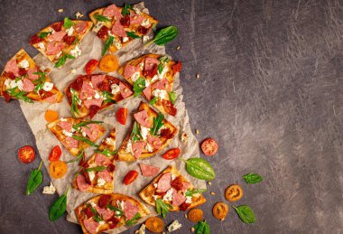 Cut into slices delicious fresh pizza with sausage and cheese on a dark background. Top view with copy space for text. Pizza on the black concrete table. flat lay. Composition with slices of delicious