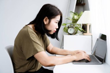 concept of Asian woman with Kyphosis: side view of laptop Work with hunched back, forward head posture, and spinal curvature clipart