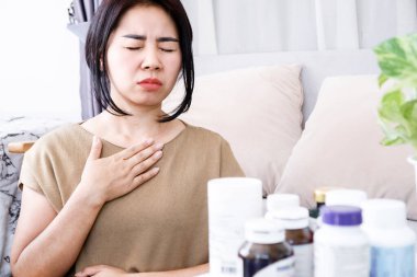Asian woman with an allergic reaction to supplements symptoms of difficulty breathing and nausea clipart