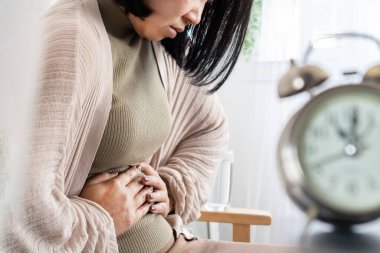 Kronik ishal geçiren Asyalı bir kadın karın ağrısını tutuyor.