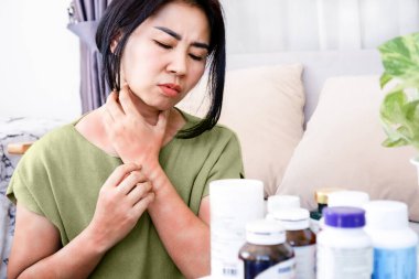 Asyalı kadının ilaca karşı alerjisi var. Multivitaminler, kaşındıran eller, bir çok ilaç şişesinin yan etkileri olan cilt kaşıntısı.
