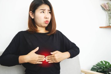 Asyalı bir kadın asit hazımsızlığı, GERD ya da mide gazından kaynaklanan epigastrik ağrıdan muzdarip.