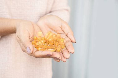 Yakın plan kadın elinde balık yağı kapsülleri, sağlık hizmetleri ve tıbbi konsept tutuyor.