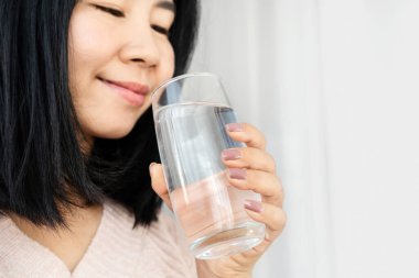 Genç Asyalı kadın bardaktan su içiyor. Yakın plan, günlük sağlıklı konsept.