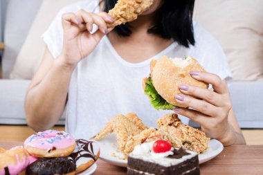 Binge eating disorder concept with woman eating fast food burger, fired chicken , donuts and desserts clipart