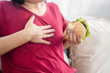 Hamburger yedikten sonra gastroözofajiyal reflü olan bir kadın.