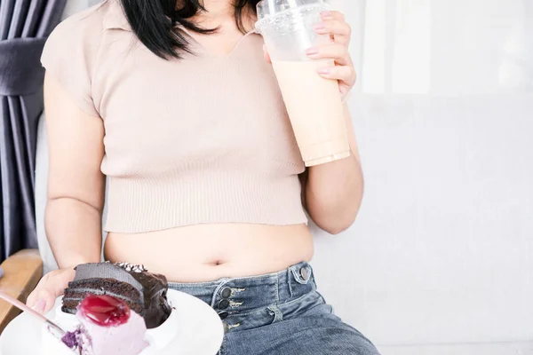 胖女人手牵着甜点和牛奶咖啡吃喝糖果 不健康的生活方式充满了糖分 — 图库照片