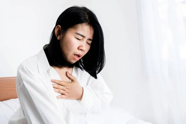 Asian woman having panic disorder in bed hand holding her chest difficult to breath