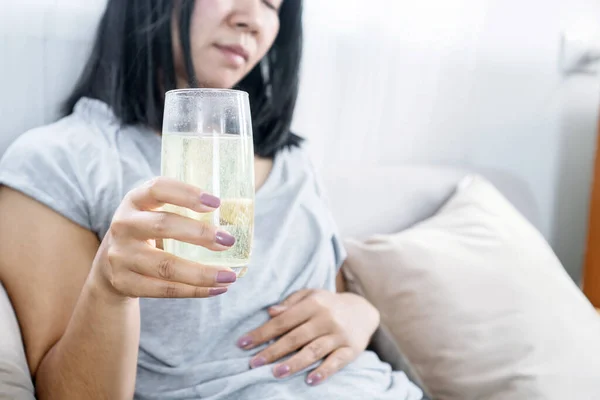 stock image woman having flatulence drinking a glass of fruit salt for relief indigestion, acidity problem hand holding her stomach ache