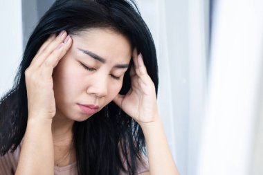 Stresli Asyalı kadın baş ağrısı çekiyor, migren ağrısı çekiyor, elini tutuyor, acı çekiyor ve yorgun.