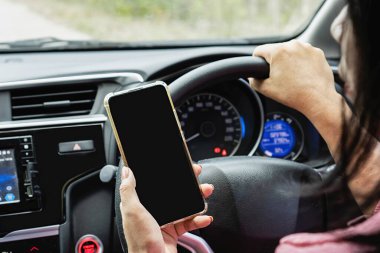 Asyalı bir kadının araba kullanırken cep telefonu kullanması riskli bir davranış. Kaza riski ve trafik kazaları, nomofobi kavramı.