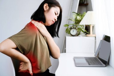 Uzatılmış bilgisayar çalışmalarından dolayı boyun, omuz ve bel ağrısı çeken Asyalı kadın.