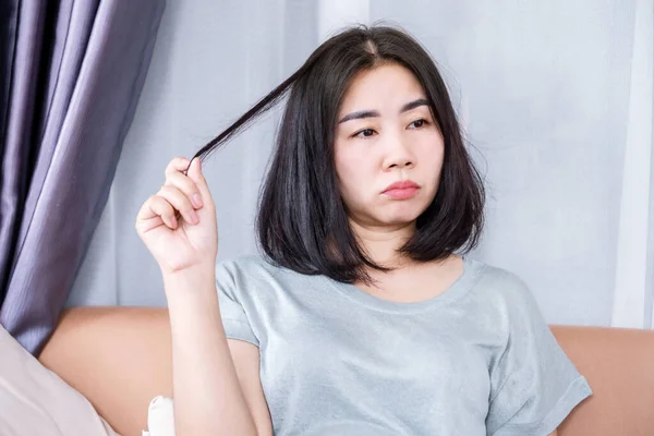 Trichotillomania (hair pulling disorder) or Body-focused repetitive behavior (BFRB) concept with Emotional Asian woman pulling out hair for Stress, Tension relief