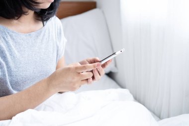 Evden alışveriş, internetten kadın eli cep telefonu siparişi, yatakta ödeme. 