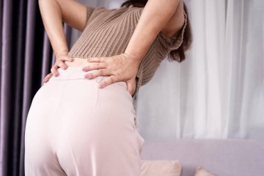 Yanlış hareket sonucu bel ağrısı çeken bir kadın.