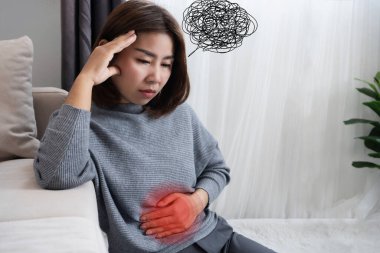 Asyalı bir kadın mide rahatsızlığı, bağırsak ekseni, rahatsızlık, acı, stres ve sindirim rahatsızlığı arasında bir bağlantı hissediyor.
